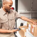 Delivery driver scanning a package in the back of a delivery van.