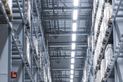 A symmetrical view down a narrow aisle between high industrial storage warehouse racks.