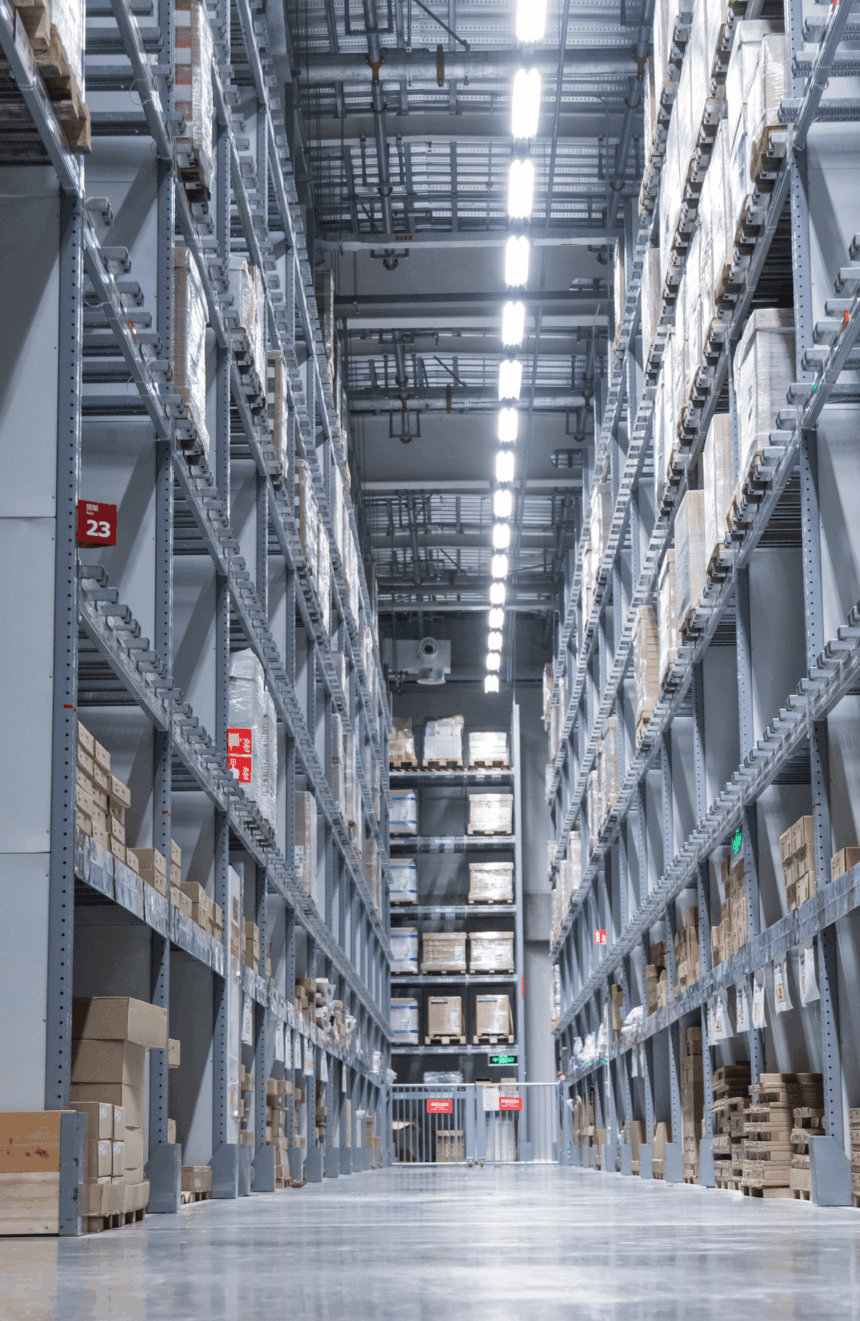 A symmetrical view down a narrow aisle between high industrial storage warehouse racks.
