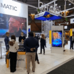 People interacting at the Dematic and Interroll trade show booths at CeMAT Australia.