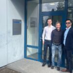 Three men standing together in front of the Wakol company office entrance.