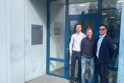Three men standing together in front of the Wakol company office entrance.