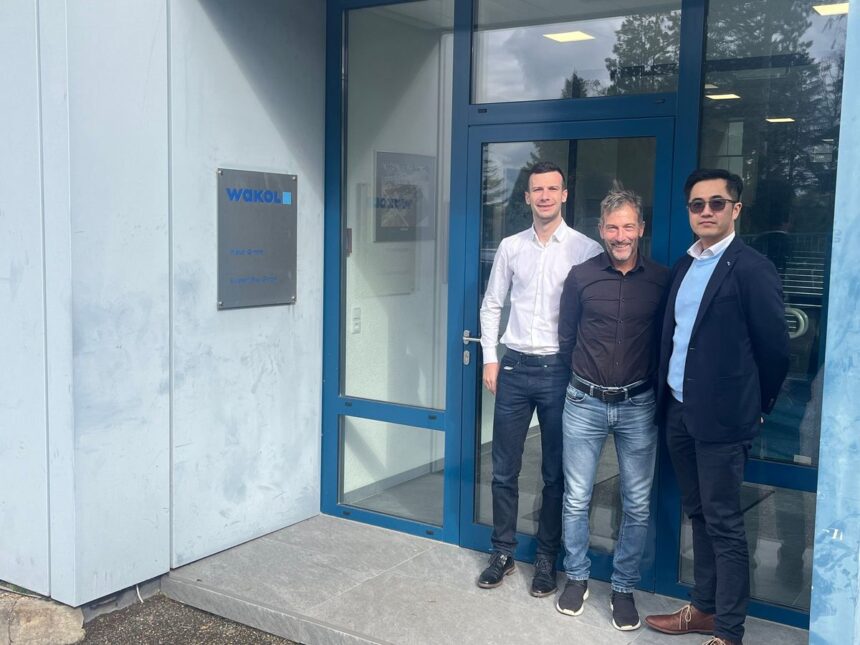 Three men standing together in front of the Wakol company office entrance.