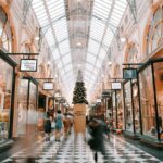 A historic indoor shopping arcade with a glass ceiling, Christmas tree, and checkered floor.
