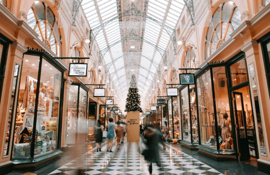 A historic indoor shopping arcade with a glass ceiling, Christmas tree, and checkered floor.