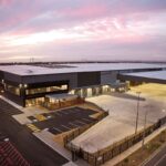 Aerial view of a large modern warehouse building at sunset.
