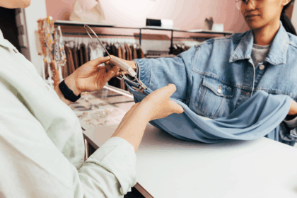 A customer and shop assistant handling a blue garment on a hanger at checkout.