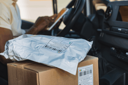 Delivery driver sitting in a van with packages in the foreground.