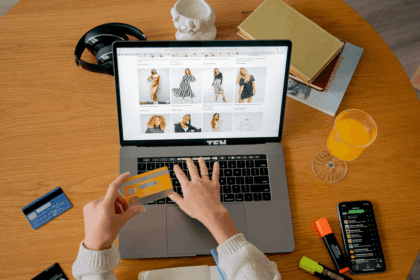 Person shopping online on a laptop with a credit card at a desk.