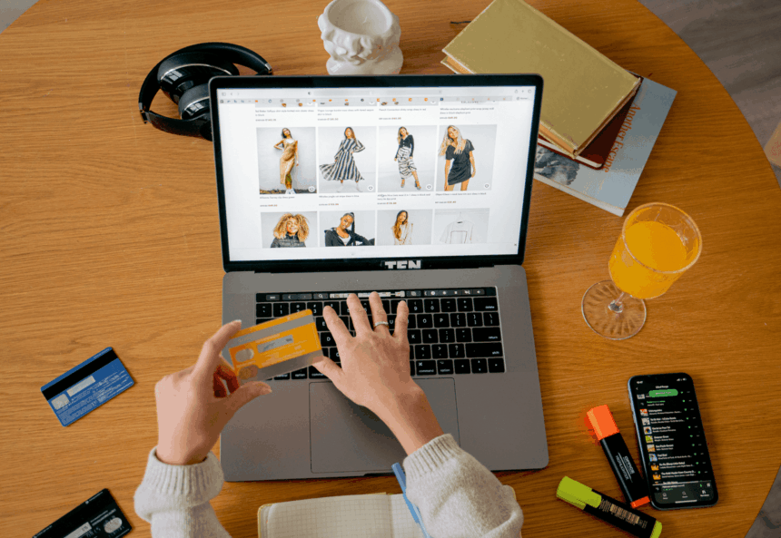 Person shopping online on a laptop with a credit card at a desk.
