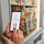 A person holds a smartphone displaying a successful order confirmation in front of a bookstore.