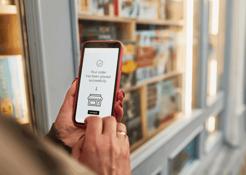 A person holds a smartphone displaying a successful order confirmation in front of a bookstore.