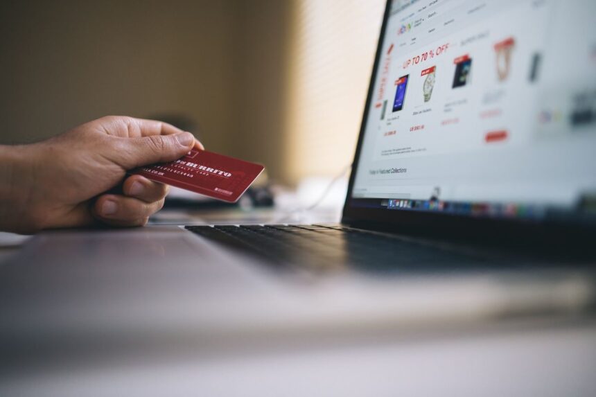 A person holding a loyalty card while shopping online on a laptop.