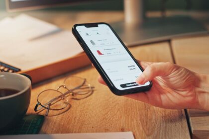 A person uses a smartphone to complete an online clothing purchase at a desk.