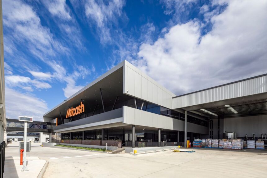 A modern, multi-story Metcash warehouse building under a blue, cloudy sky.