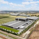 Aerial view of a large modern warehouse facility in an industrial landscape.