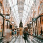 People walk through the brightly lit, historic Royal Arcade in Melbourne with a Christmas tree.