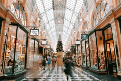 People walk through the brightly lit, historic Royal Arcade in Melbourne with a Christmas tree.