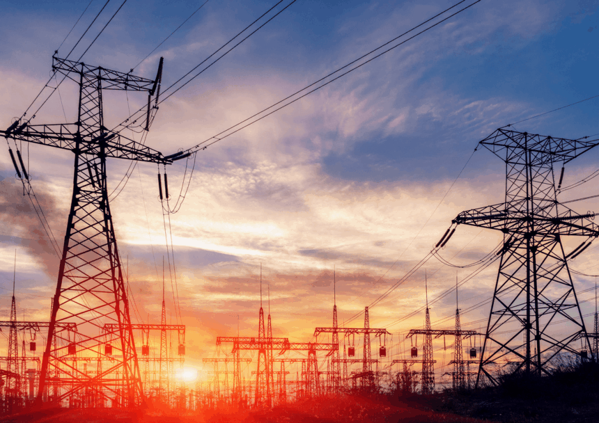 High-voltage power lines and electrical towers silhouetted against a vibrant sunset sky.