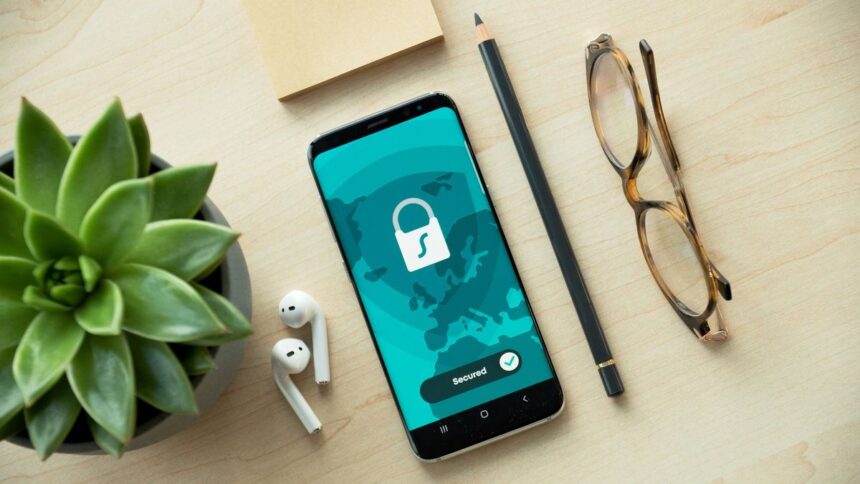 A smartphone showing a secured padlock icon on a desk with accessories.