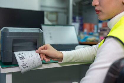 A worker pulls a shipping label printed from a thermal printer in a warehouse.