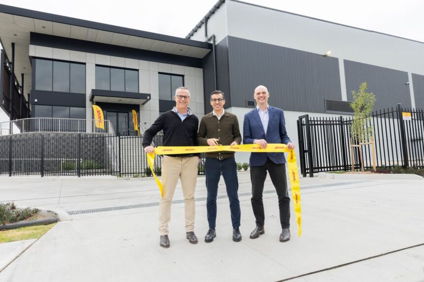 Three men cut a yellow DHL ribbon at a new warehouse opening.