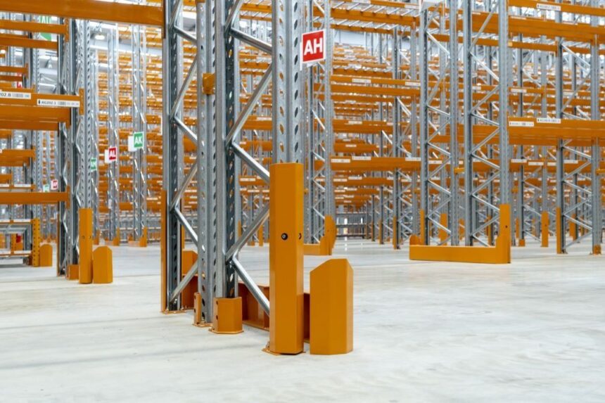 Empty warehouse featuring tall industrial metal shelving units with yellow protective guards.