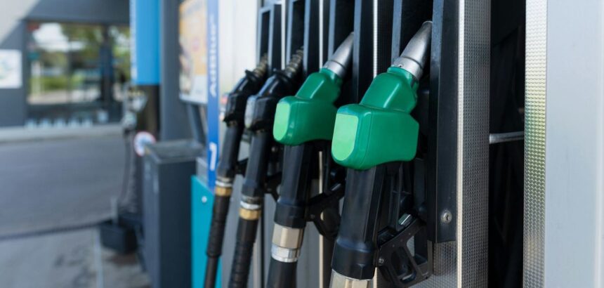 Close-up of several green-handled fuel pump nozzles at a gas station.