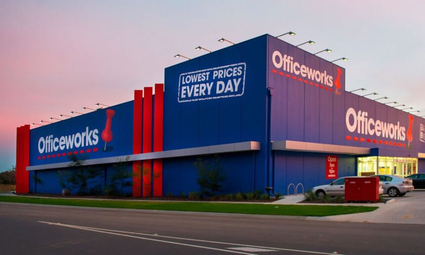 An Officeworks store exterior with a blue building, red accents, and sunset sky background.