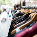Clothing items hanging on a rack at an outdoor market.