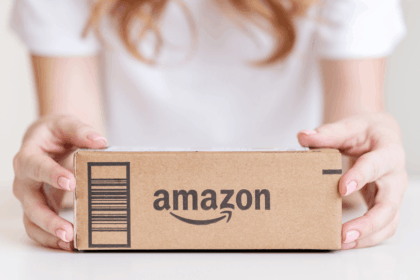 A person holding a brown cardboard Amazon package.