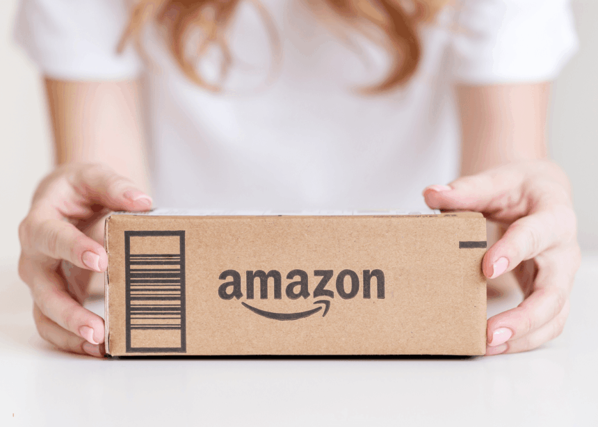 A person holding a brown cardboard Amazon package.