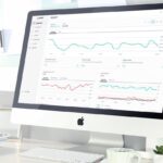 A desktop computer monitor displaying a business analytics dashboard with data graphs.