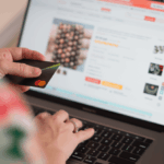 Person shopping online on a laptop while holding a credit card.