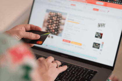 Person shopping online on a laptop while holding a credit card.