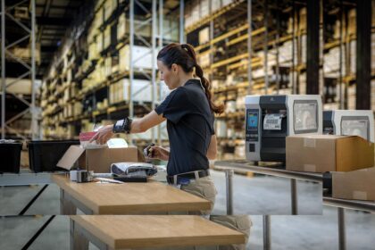 Warehouse worker processing shipping labels at a packing station.