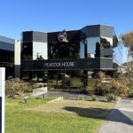 Peacock House office building with Peacock Bros. signage and direction board on sunny day.
