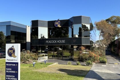 Peacock House office building with Peacock Bros. signage and direction board on sunny day.