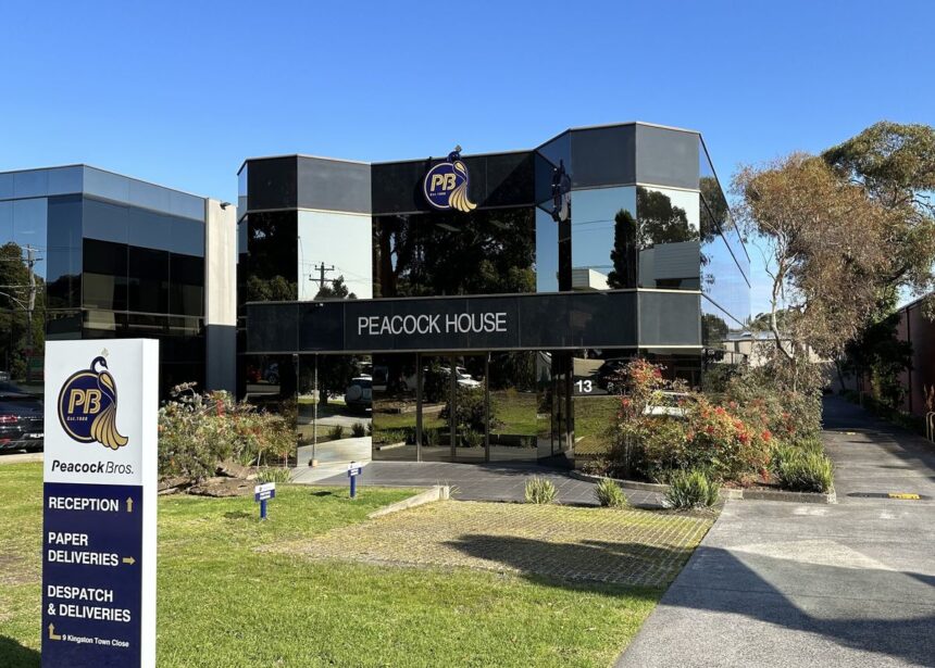 Peacock House office building with Peacock Bros. signage and direction board on sunny day.