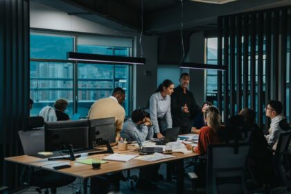 A diverse group of professionals collaborates in a modern office during an evening meeting.