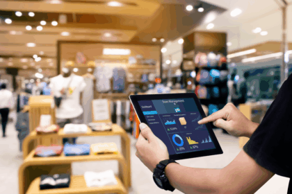 A person uses a tablet displaying a store management dashboard in a clothing store.