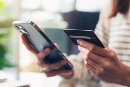 Close-up of a person holding a smartphone and a credit card for online shopping.