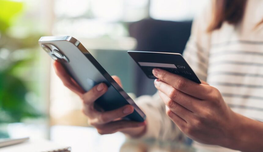 Close-up of a person holding a smartphone and a credit card for online shopping.