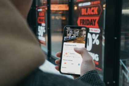 A person holding a smartphone showing a MediaMarkt store location in front of a storefront.