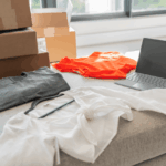 Clothing, shipping boxes, and a laptop arranged on a table for online retail processing.