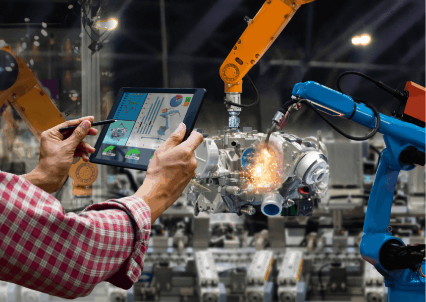 A person uses a tablet to monitor industrial robotic arms welding a car engine.