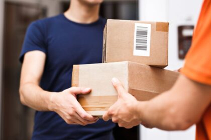 A delivery person handing a cardboard package to a recipient.