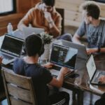 A group of people sitting around a table working on their laptops.