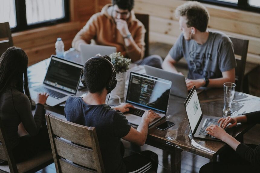 A group of people sitting around a table working on their laptops.