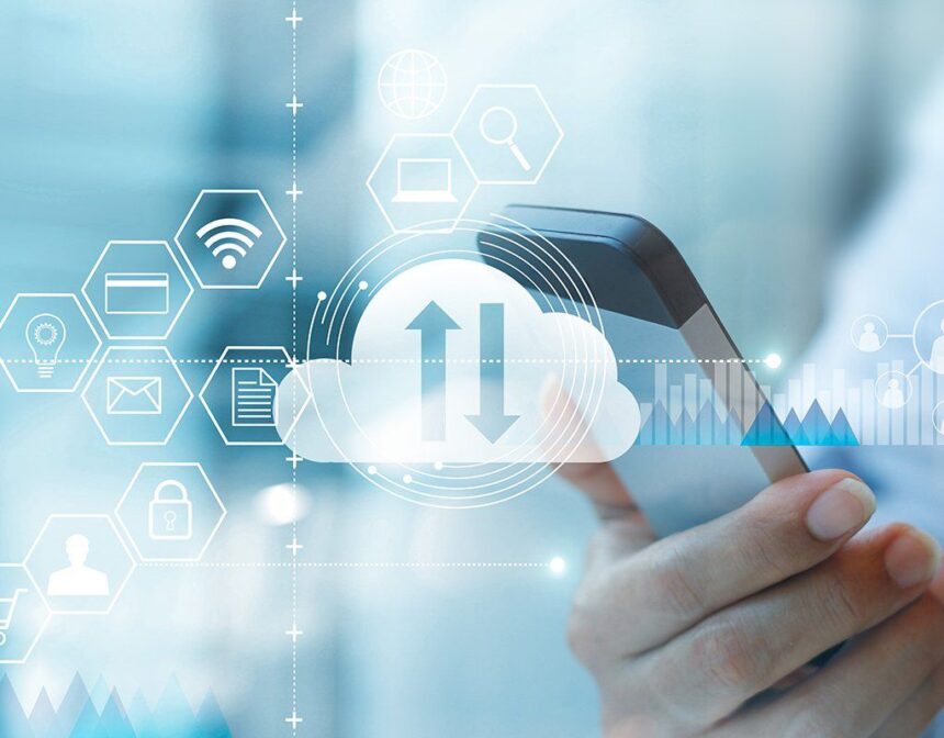 Hand holding a smartphone with digital cloud data synchronization and business icons overlay.